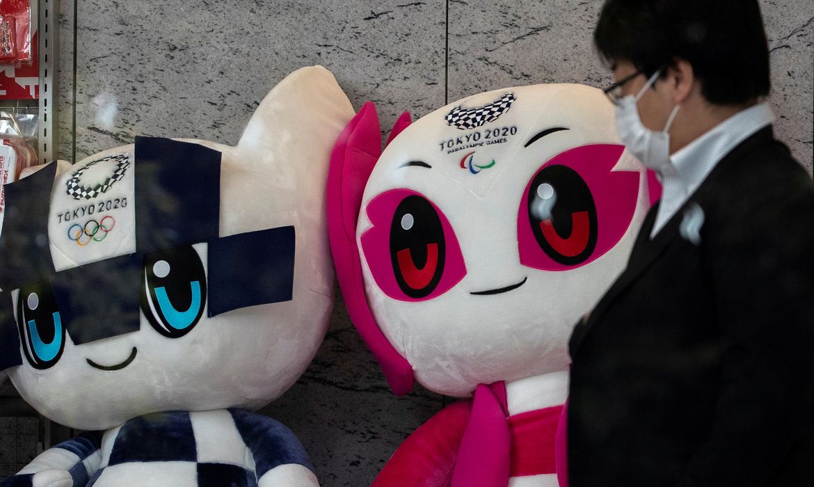 A man wearing a protective face mask, following an outbreak of the coronavirus disease (COVID-19), walks past Tokyo 2020 Olympic Games mascot Miraitowa and Paralympic mascot Someity plushies at a building in Tokyo