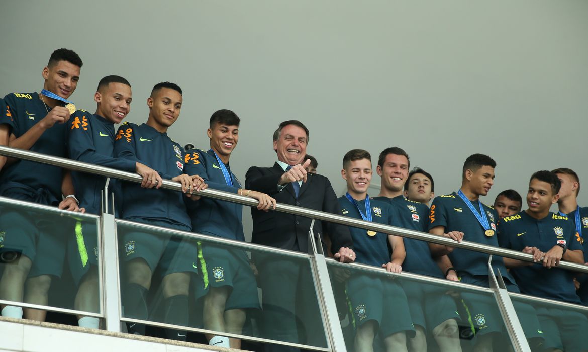 O presidente Jair Bolsonaro parabeniza e posa para foto com a Seleção do Brasil Sub-17 que conquistou ontem (17),  em Brasília, o tetracampeonato do Mundial de Futebol da categoria.