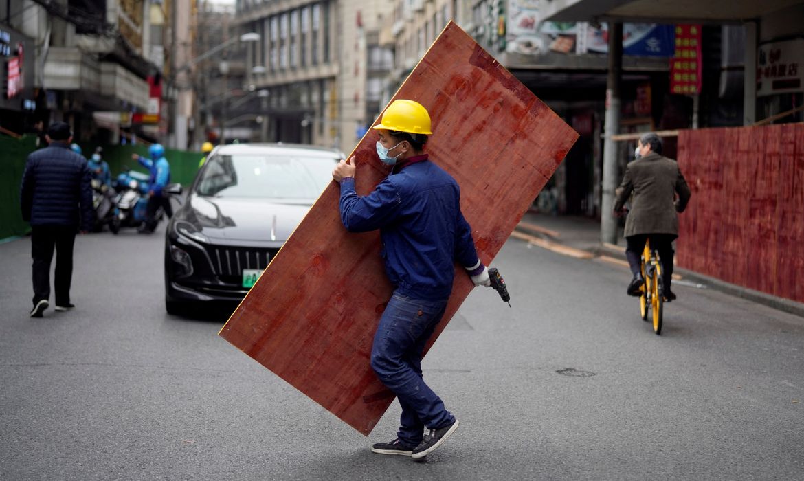 Funcionário monta barreiras em rua de Xangai para criar área isolada durante lockdown da Covid-19