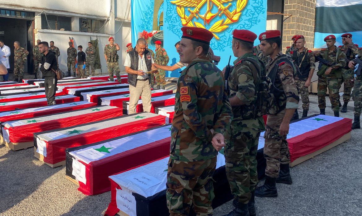 Military police stand near coffins with the bodies of some of the people who were killed in a drone attack on a military academy, outside a military hospital in Homs. REUTERS/Firas Makdesi